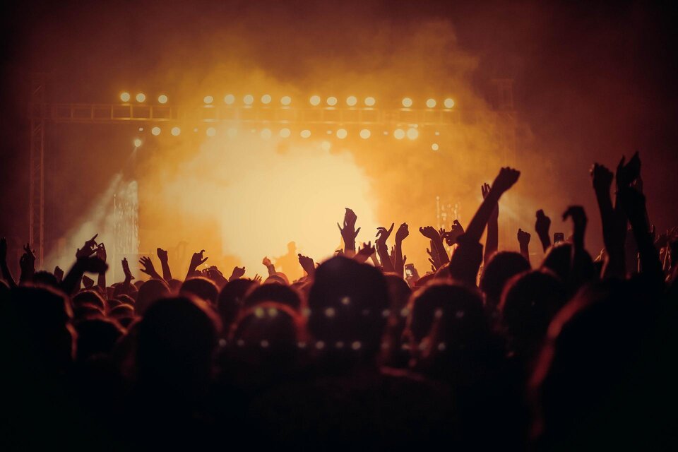 Eine Menschenmenge bei einem Konzert mit erhobenen Händen. Helle Lichter leuchten im Hintergrund und schaffen eine aufregende Atmosphäre. | © Pixabay