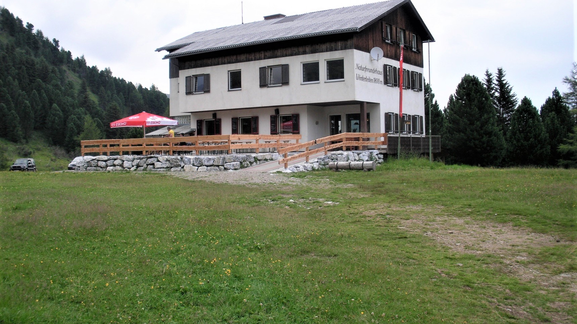 Ein gemütliches Gebäude in der Natur, umgeben von grünen Wiesen und Bäumen. Die Terrasse bietet einen Blick auf die Landschaft. | © Winterleitenhütte